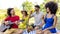 Summer holidays outdoor picnic. multiracial group of friends having food and drinking beers laying on a blanket in a park garden.