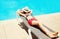 Summer holidays - woman lying resting on a deckchair over a blue water pool