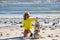 Summer kid meditation. Child play with pyramid stones balance on the sand of the beach. Kid with stack of stones on sand