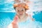 Summer kids in water in pool underwater. Funny kids face underwater. Underwater child swims in pool, healthy child