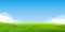 Summer landscape background. Field or meadow with green grass, flowers and hills. Horizon line with blue sky and clouds.