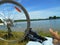 Summer landscape bike whell and barefoot legs girl resting on a lake blue sky background