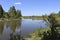 Summer landscape - A calm flat river among fields and birch groves under a blue sky.