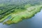 Summer landscape. dirt road passing through green forest on lake shore. aerial photo