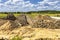 Summer landscape with a dug trench for a pipeline in the middle of a green field