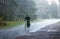 Summer landscape - an elderly cyclist riding a country road in the pouring rain