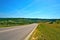 Summer landscape - highway stretching into the distance among forests and fields.