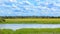 Summer landscape with lake field and clouds