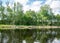 Summer landscape with lake and white cloud reflections in the water, tree silhouettes reflect in the lake water