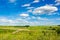 Summer landscape with meadows, roads and forests and a clear blue sky with clouds. Local travel