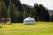 Summer landscape in the mountains. Tall trees of a Christmas tree, the national dwelling is a yurt. Kyrgyzstan Tourism and travel