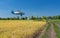 Summer landscape with an old airplane flying over an agricultural field