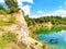 Summer landscape with old basalt quarry and sunken excavator in lake by blue sky