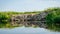 Summer landscape, river bank pollution, concrete blocks thrown into the river, reflections in the water