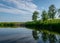 Summer landscape, river bank pollution, concrete blocks thrown into the river, reflections in the water