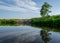 Summer landscape, river bank pollution, concrete blocks thrown into the river, reflections in the water