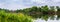 Summer landscape with river and thickets of reeds and trees on the opposite bank, panorama