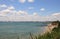 Summer landscape of the sea and green grass. Sandy beach and blue water with sky and white clouds. Sunny beach in Bulgaria on the