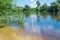 Summer landscape of the small sandy beach on the river with green trees on the banks