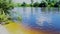 Summer landscape of the small sandy beach on the river with green trees on the banks and clouds reflecting in water.