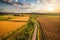 Summer landscape at sunset. Farm, agricultural fields, countryside, country road. Generative AI