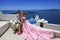 Summer love. Beautiful happy young couple in wedding clothes is posing near Church of the Three Bells in Fira in Santorini.