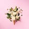 Summer minimal concept. Ice cream cone with white flowers and leaves on pink background. Flat lay. Top view. Creative layout.