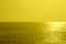 Summer minimalist background, yellow monochromatic glittering sunset on the sea