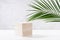 Summer modern showcase with cube wooden podium with green palm leaf in sunlight, shadow on white board, grey marble wall, cosmetic