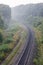 Summer morning landscape. Empty railroad turn in sunrise mist