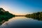 Summer nature panorama at sunset, forest trees and river with reflection in water, vivid tranquil and relax background