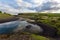 Summer nature scenery with black sand on a riverbank and clouds in the sky.