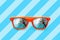 Summer orange sunglasses with palm trees reflections isolated in blue background with diagonal stripes