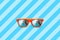 Summer orange sunglasses with palm trees reflections isolated in large blue background with diagonal stripes.
