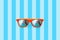Summer orange sunglasses with palm trees reflections isolated in large blue background with stripes.