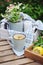 Summer outdoor breakfast with tea, lemon and bouquet of chamomile flowers on wooden table