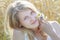 Summer outdoor head and shoulders portrait of blonde girl at cereal ears field background