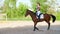 Summer, outdoors, girl rider, jockey riding on a thoroughbred beautiful brown stallion, horse, on the training ground