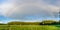 Summer panorama with a semicircle of a rainbow