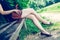 Summer in the park: Young woman in sexy black dress and ballerinas is sitting on a park bench