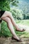 Summer in the park: Young woman in sexy black dress and ballerinas is sitting on a park bench