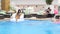 Summer party girl in swimsuit makes beautiful jump into blue pool on background group people