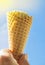 Summer, party, hand holding a vanilla ice cream cone against the blue sky and sunlight