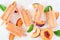 Summer peach yogurt ice pops, top view scattered on white marble