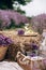 Summer picnic in the lavender field. A glass of white wine, a picnic basket, snacks and a bouquet of flowers on a haystack among