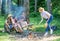 Summer picnic. Tourists hikers sit on log relaxing waiting picnic snack. Picnic with friends in forest near bonfire