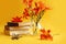 Summer pictures: orange daylilies in a glass vase near a stack of books, a bunch of old keys, yellow background, space for text