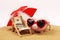 Summer piggy bank with heart sunglasses standing on sand under red and white sunshade next to beach chair with towel from