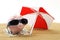 Summer piggy bank standing on towel from greenback hundred dollars with sunglasses on the beach sand under red and white sunshade