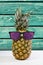 Summer pineapple in sunglasses on wood background